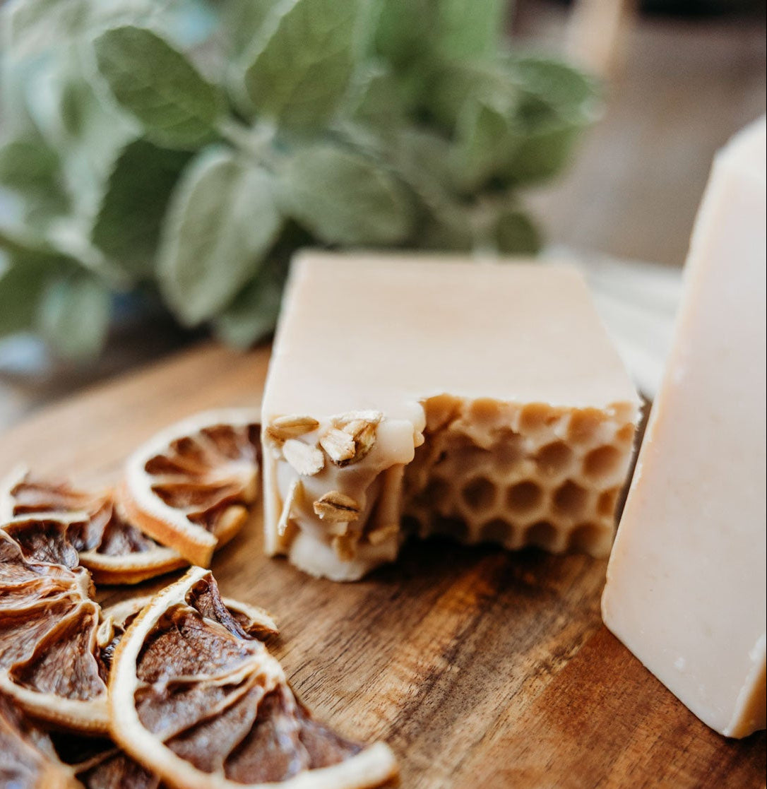 Honey oat milk soap with honeycomb  pattern and dried citrus slices on a wooden board.